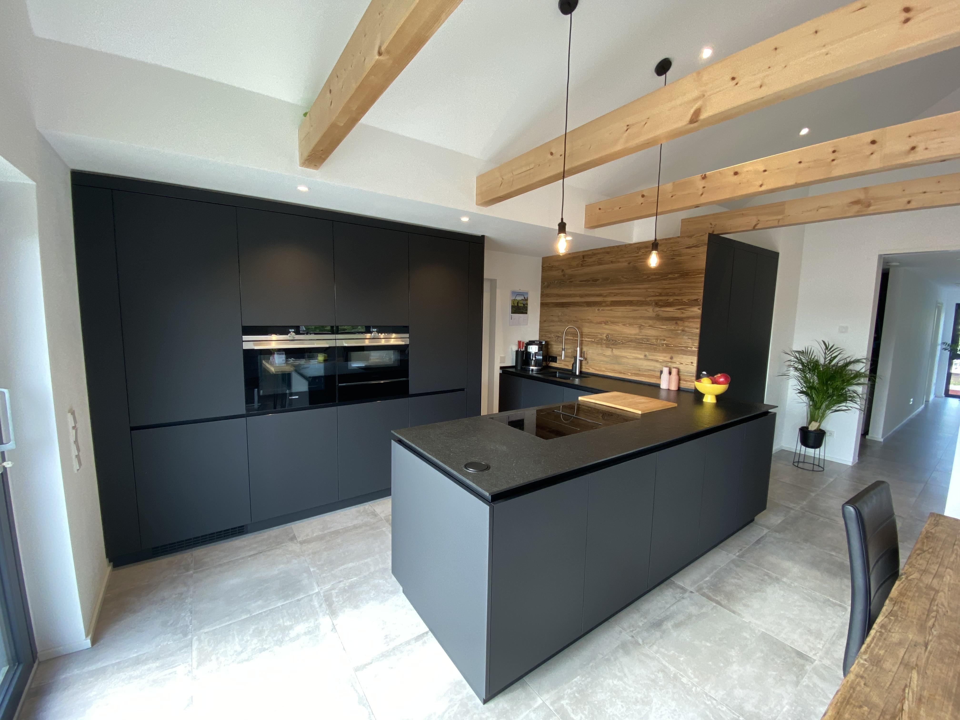 Dunkle Küche mit Küchenzeile und einer Insel und einer Holzrückwand