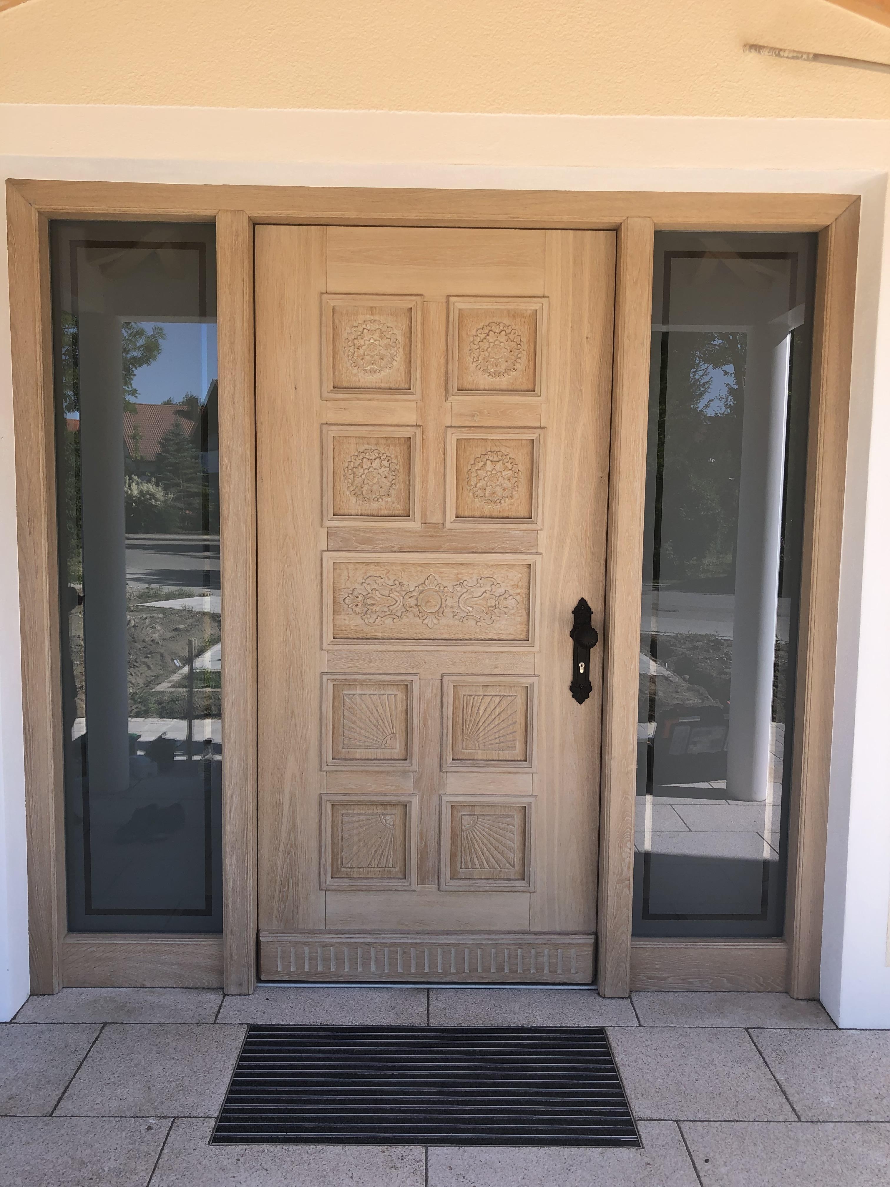 Hauseingangstür aus hellem verzierten Holz