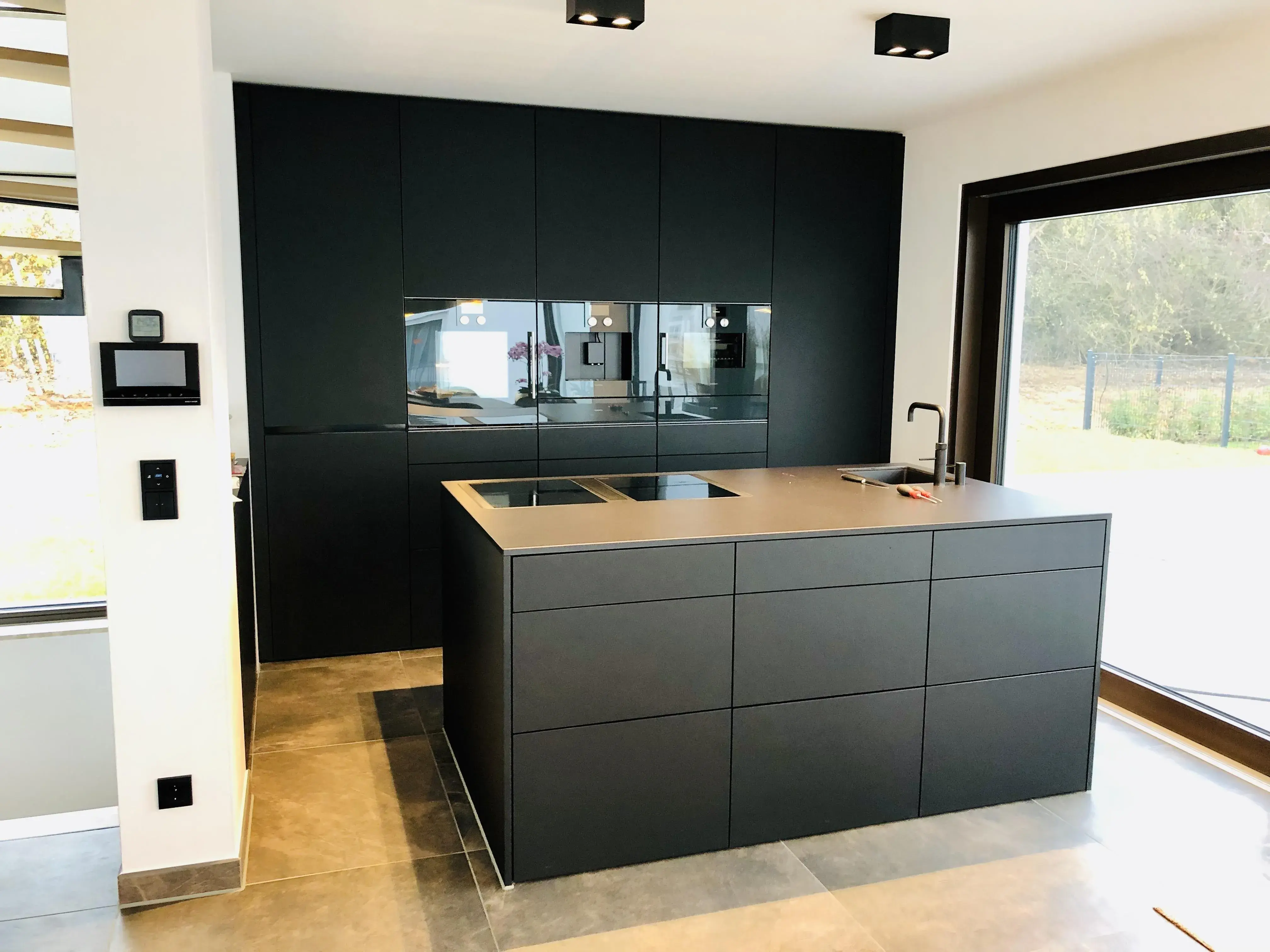 Push to open Küche mit Hochschrankzeile und Kücheninsel in schwarz