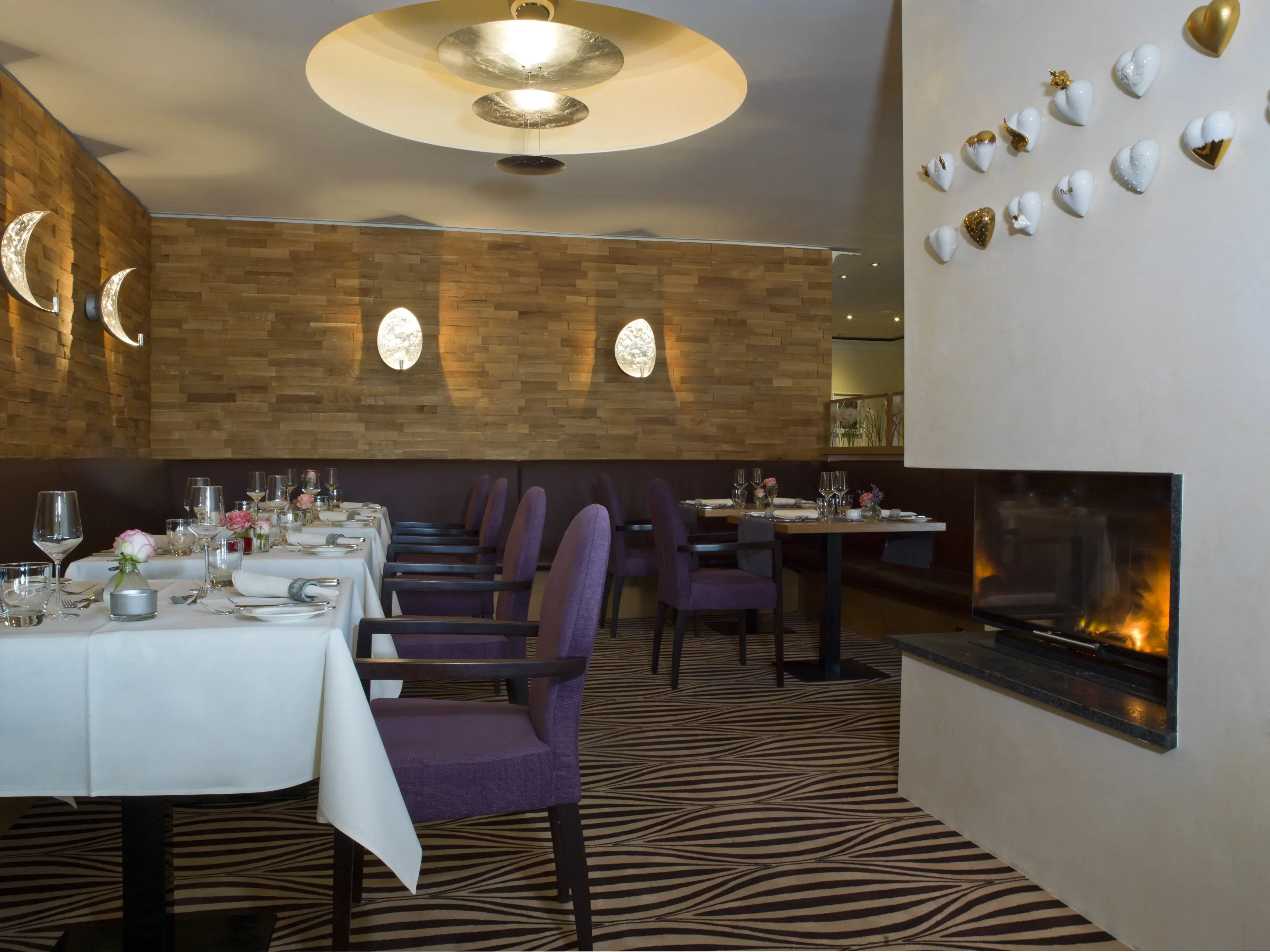 Restaurantbereich mit vielen Tischen und einem Kamin