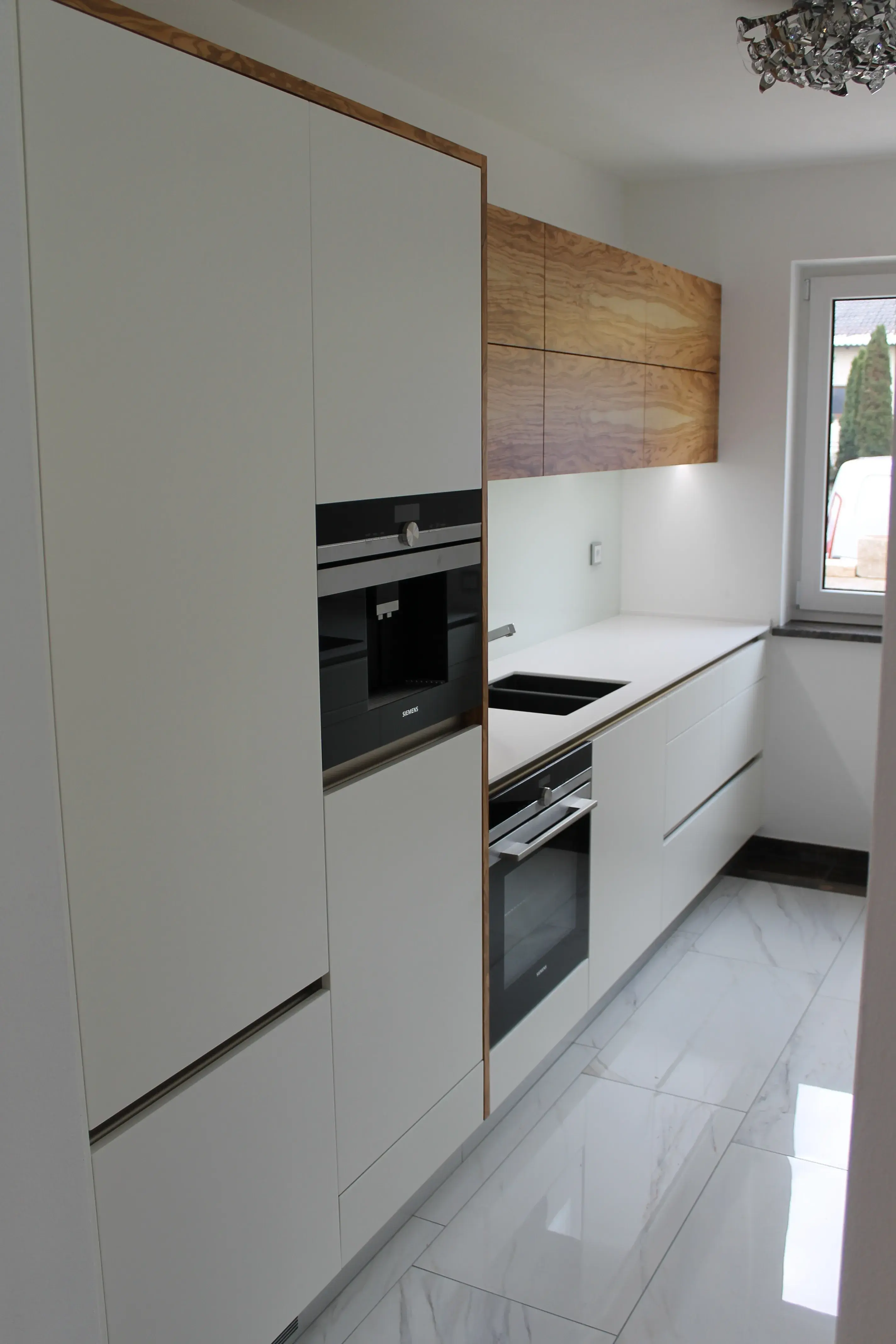 Weiße, grofflose Küche mit Hängeschränken in Holz abgesetzt