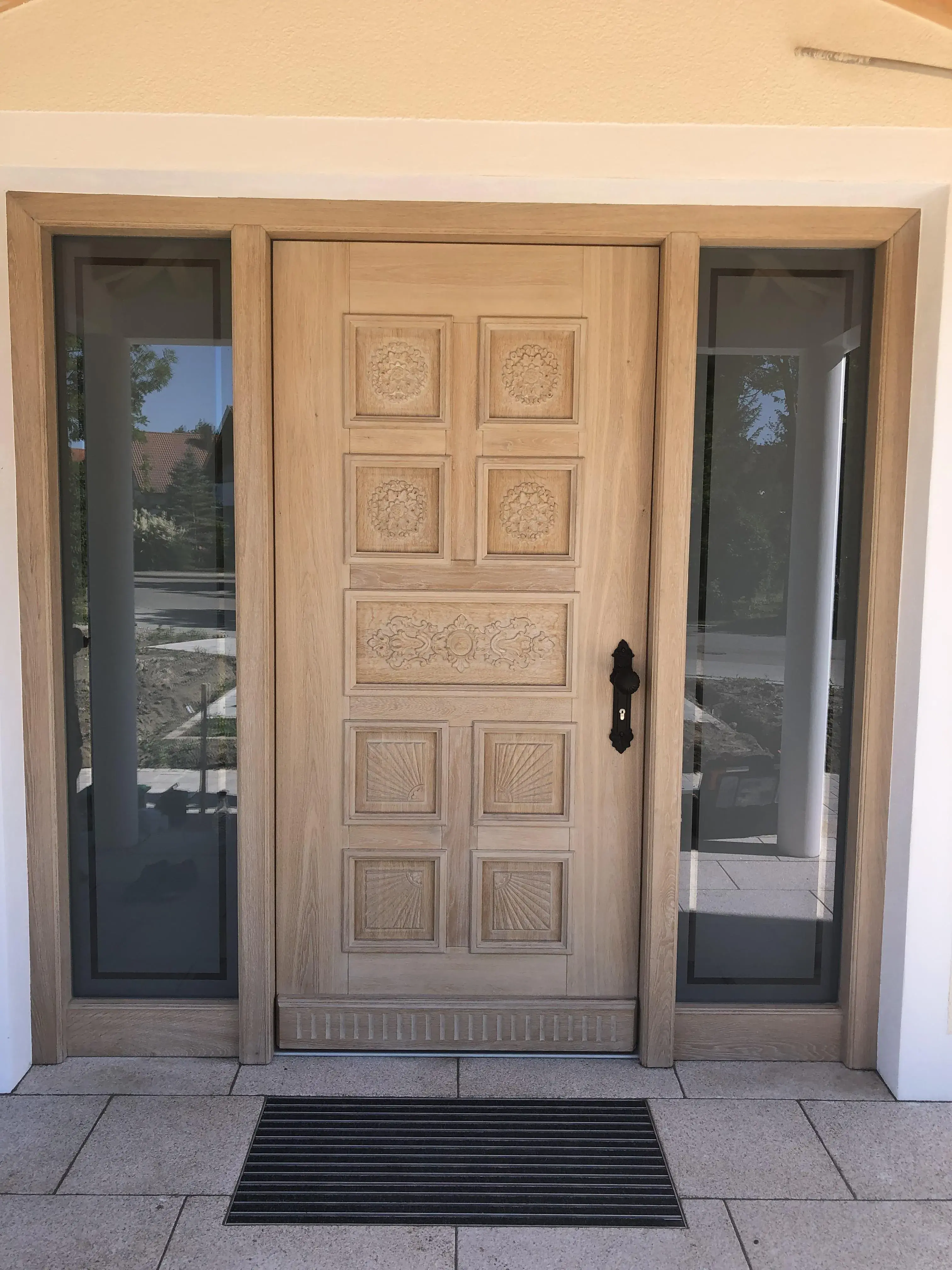 Hauseingangstür aus hellem verzierten Holz